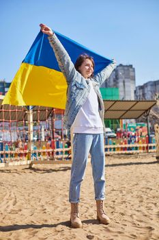 Portrait of a joyful Ukrainian woman holding a child and a Ukrainian flag. The girl is waiting for her husband from the war. War between Russia and Ukraine