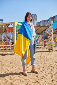 Portrait of a joyful Ukrainian woman holding a child and a Ukrainian flag. The girl is waiting for her husband from the war. War between Russia and Ukraine