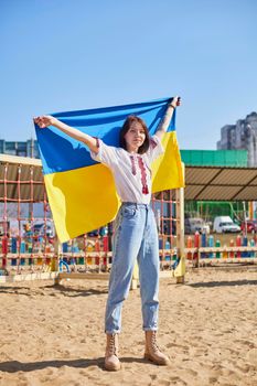Portrait of a joyful Ukrainian woman holding a child and a Ukrainian flag. The girl is waiting for her husband from the war. War between Russia and Ukraine