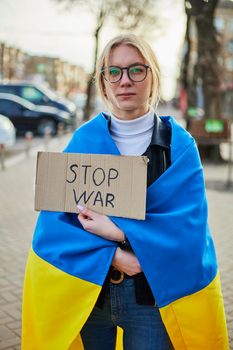 Portrait of a joyful Ukrainian woman holding a Ukrainian flag and a sign. The girl is waiting for her husband from the war. War between Russia and Ukraine