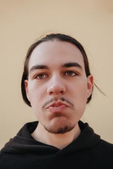 young Caucasian guy bites sour unripe citrus. A man makes a face because of the sour taste of fruit, posing on a green background. Vitamin C. Weak sensitive tooth enamel.