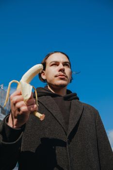 killer man with a banana instead of a gun. angry and confident look. Portrait of a nerd with mustache holding a banana weapon in his hand.