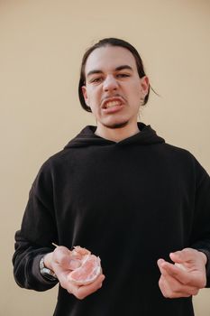 young Caucasian guy bites sour unripe citrus. A man makes a face because of the sour taste of fruit, posing on a green background. Vitamin C. Weak sensitive tooth enamel.