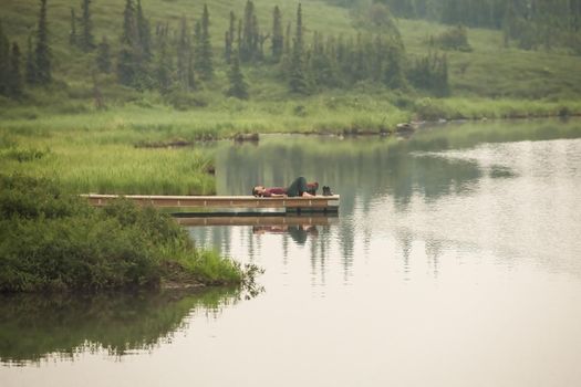 Meditating Hiker resting on a dock in Denali National Park