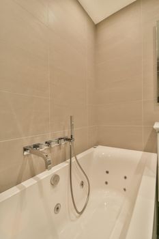 Ceramic bathtub in the bathroom in beige design in a modern house