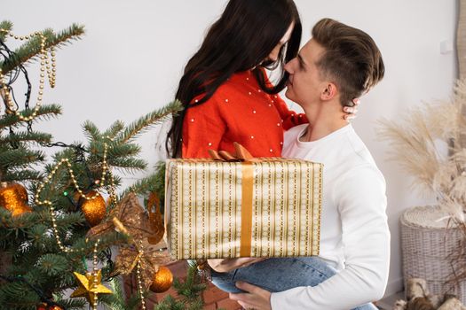 The fiance lifted his partner up in a fit of joy. Lovers flirt in a decorated living room at home. December Christian holidays.