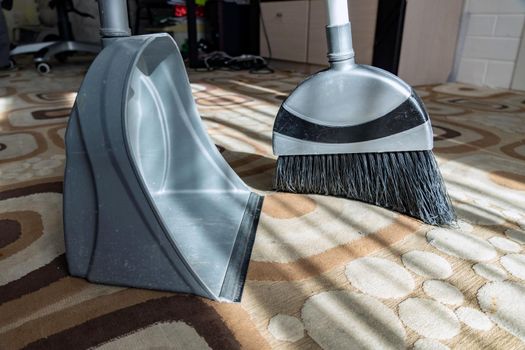 Cleaning.Clean up the garbage from the floor with a broom for cleanliness.Sweep away dust and dirt with a brush into a dustpan.Sweeping the carpet with a broom at home.Indoor cleaning tools.