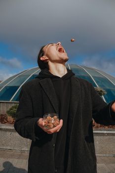 Young gay hipster eating peanuts at the street smiling happy sunglasses. Healthy lifestyle