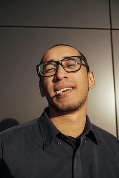 Man smoking a white paper joint close up. Sungles black background