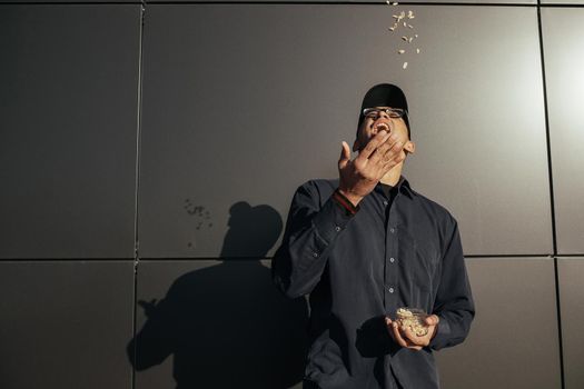 Young african american man holding peanuts on black background street