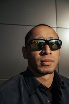 Portrait angry man screaming in studio. Closeup african american guy shouting on black background. Male model aggressive face expression. Serious man take off sunglasses. Displeased customer client