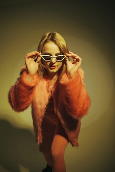 Fashion model in pink suit and sunglasses. Studio shot.