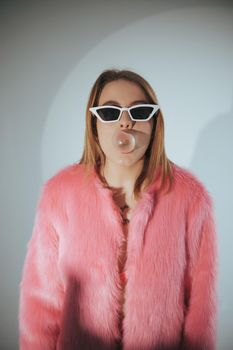 Fashion model in pink suit and sunglasses. Studio shot.