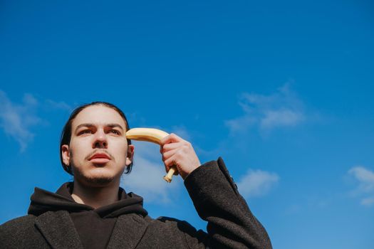 young gay hipster make banana suicide at the street. sky
