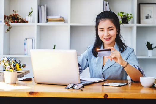 Online Shopping and Internet Payments, Portrait of Asian woman are using their credit cards and laptop computer to shop online or conduct errands in the digital world