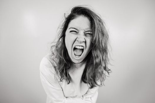 Close-up portrait of insane woman in straitjacket on white background. Monochrome