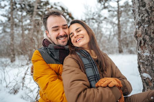 Young couple in love outdoor in snowy winter forest having a walk
