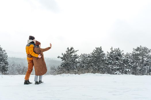 Young couple in love outdoor in snowy winter forest having a walk