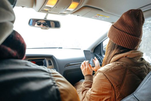 Beautiful young woman wearing warm clothes sitting in car while winter road trip, close up