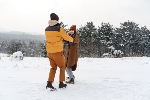 Young couple in love outdoor in snowy winter forest having a walk