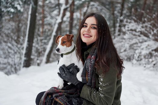 Pet is have more important things than posing for photoshoot. Smiling brunette having fun while walking with her dog in the winter park.