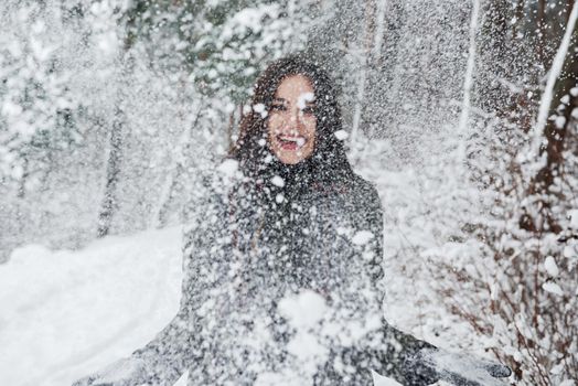 Playful young girl standing outdoors and throwing up the snow. Conception of winter.