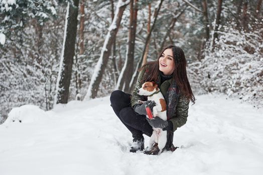 Where should we go. Smiling brunette having fun while walking with her dog in the winter park.