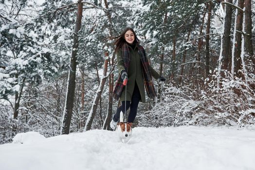 Morning run. Woman in warm clothes walks the dog in the snowy forest. Front view.