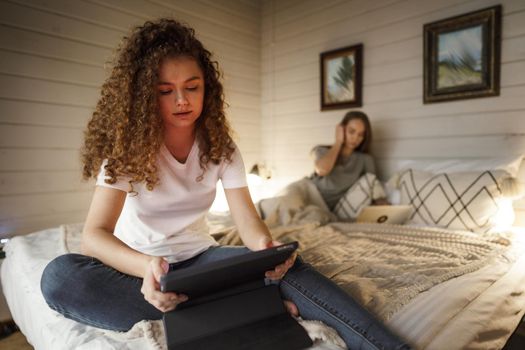 Two beautiful women lying in bed, holding and watching laptop