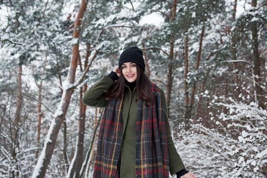 Charming woman. Cheerful young girl in warm clothes have a walk in the winter forest at daytime.