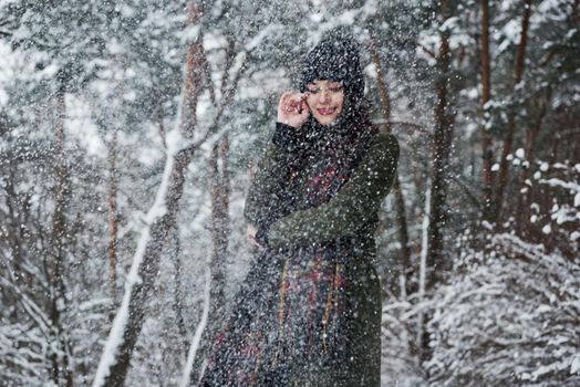 That is beautiful snowfall. Cheerful young girl in warm clothes have a walk in the winter forest at daytime.