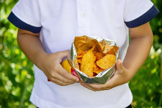 potato chips in the boy's hand, the boy eats the chips. selective focus