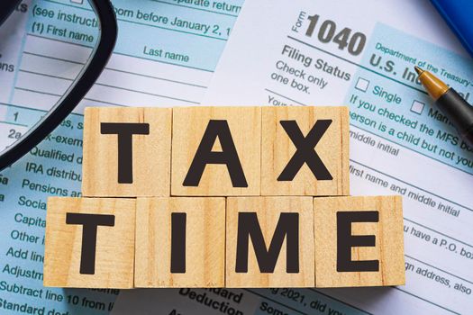 Tax time with Alphabet wooden block cube with Tax forms 1040. U.S Individual Income Tax Return on a desk. Business and tax concept. 