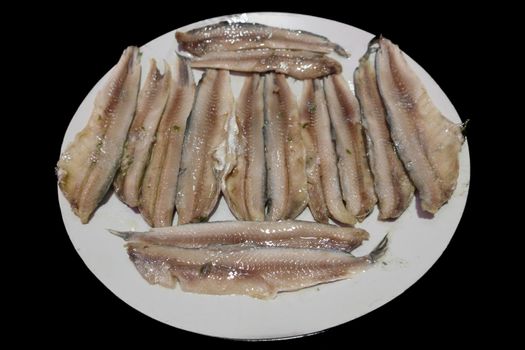 Raw anchovy slices plate over black background