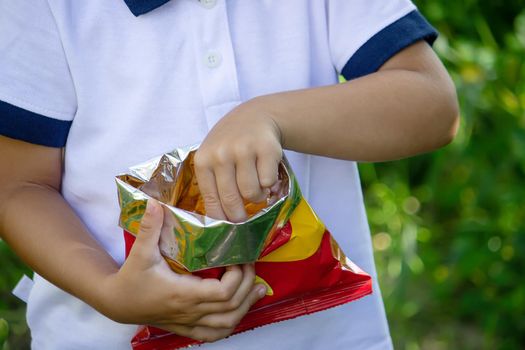 potato chips in the boy's hand, the boy eats the chips. selective focus
