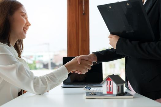 Estate agent and customer shaking hands after finished contract after about home insurance and investment loan.