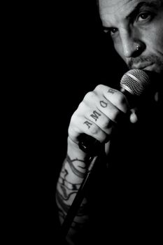 Singer man with round microphone on dark background. Copy space