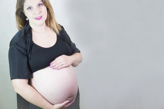 Eight month pregnant woman with bare belly. Happy emotion