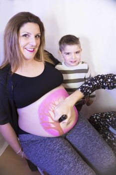 Eight month pregnant woman with three year old son. Body painting