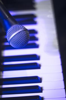 Microphone over piano keys in dim light. No people