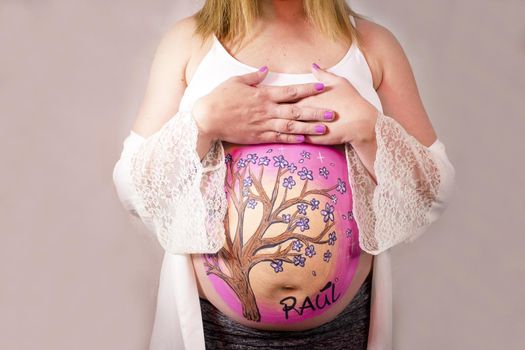 Eight months pregnant woman in dressing gown with drawing on her belly. No copy space
