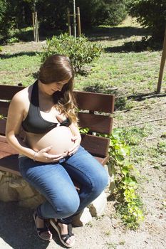 Seven month pregnant woman in a park dressed in jeans