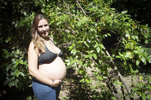 Seven month pregnant woman in a park dressed in jeans