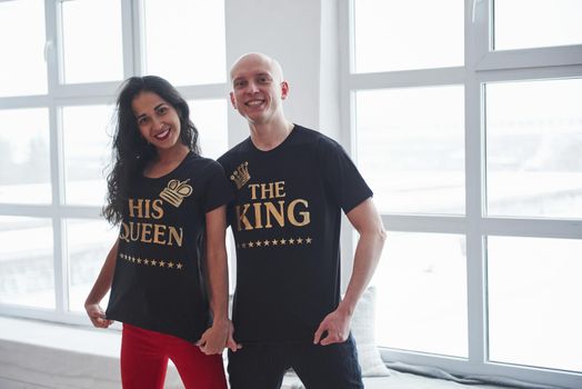 Golden colored inscriptions. The king and his queen. Man and woman in black shirts standing in the room near the windows.
