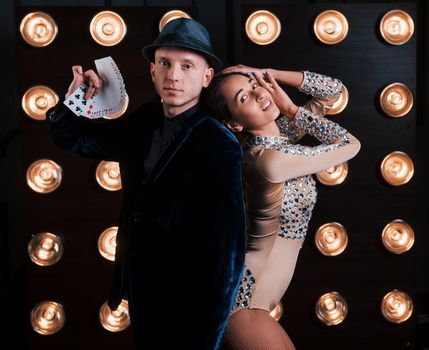 Guy showing the cards, girl is leaning on him. Happy couple posing for the portrait. Family business of magician tricks and shows.