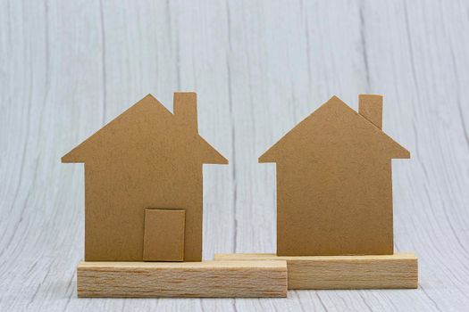 House brown paper model on white wooden background. Property investment and tax concept.