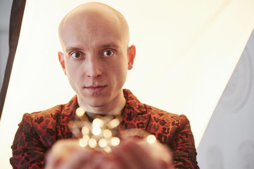 Guy in the classic holiday wear holding New year garlands in front of the camera.
