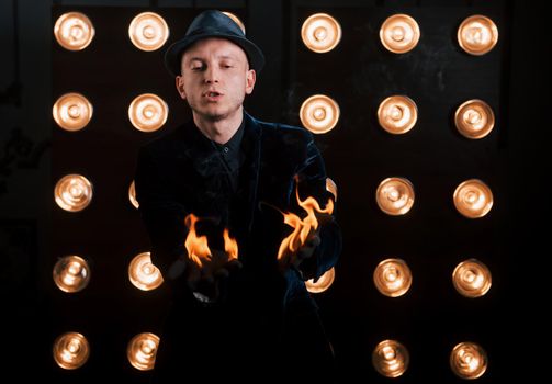 Burning nice. Professional illusionist in black hat, shirt and gloves playing with fire.