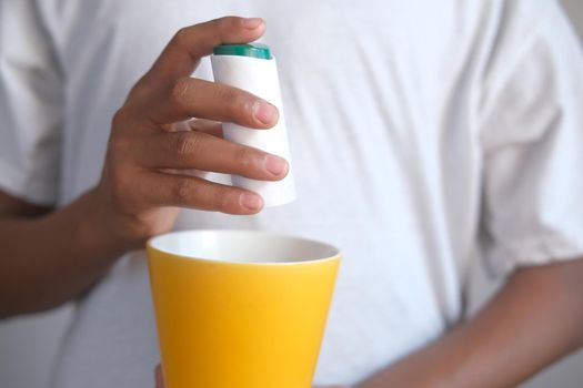 young man putting artificial sweetener in tea