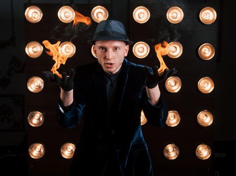 Flames from the hands. Professional illusionist in black hat, shirt and gloves playing with fire.